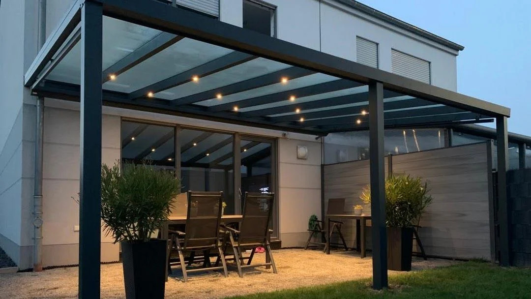 Modernes anthrazitfarbenes Terrassendach mit integrierter LED-Beleuchtung am Abend